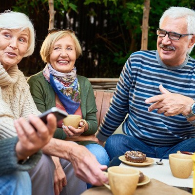 Group of friends smiling and talking while enjoying an outdoor patio