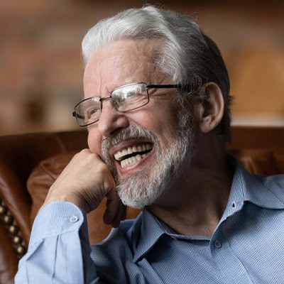 Man smiling in a leather chair while propping up his chin with his fist